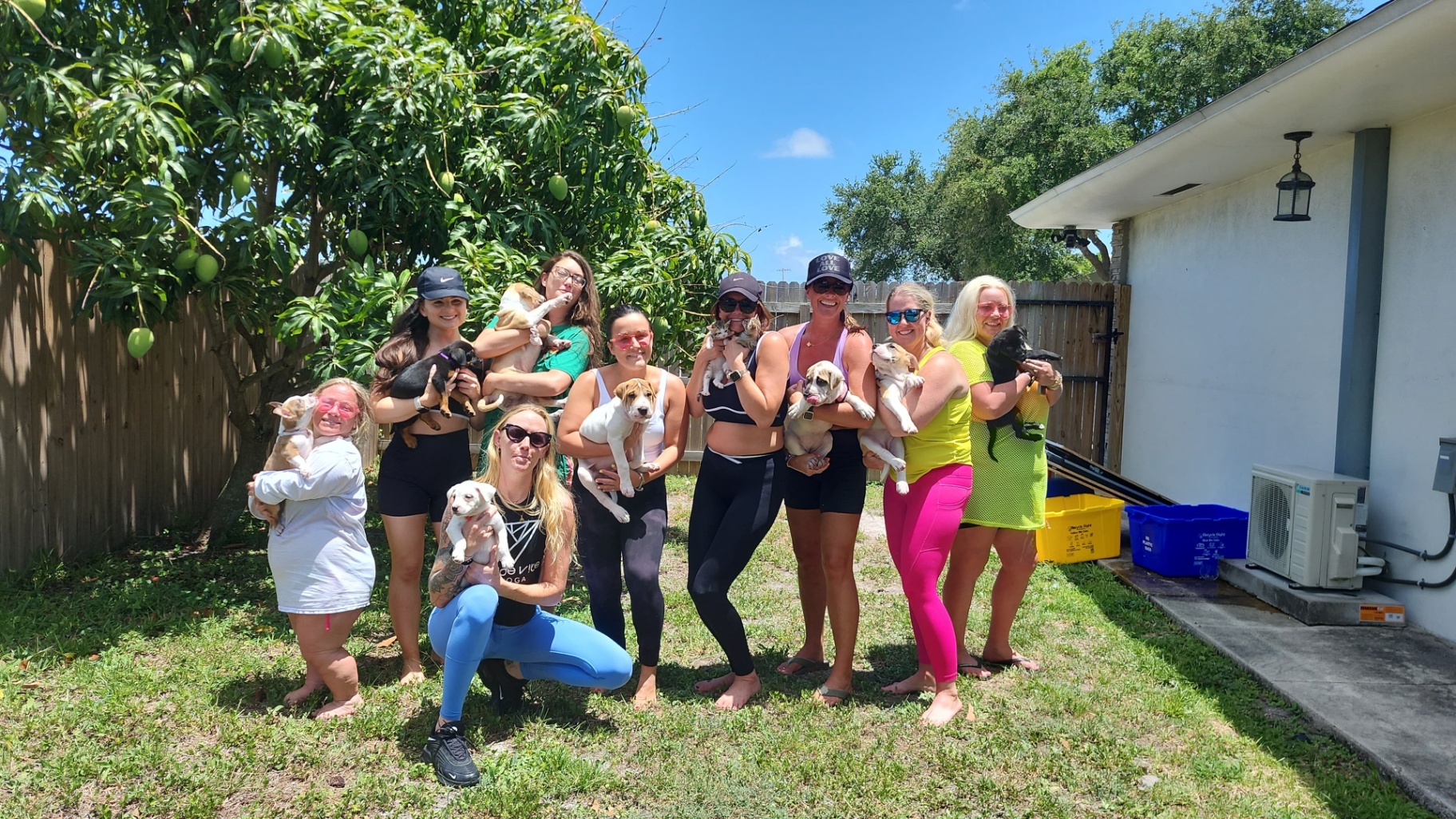 Palm Beach group of guests in colorful athleisure cradling rescue puppies outside